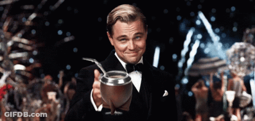 A Man In A Tuxedo Is Holding A Silver Cup With A Straw In It GIF