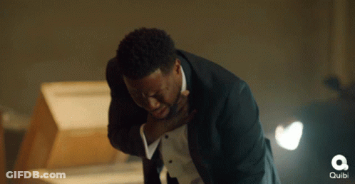 A Man In A Tuxedo Is Holding His Chest In Pain And The Word Quibi Is Visible In The Background GIF