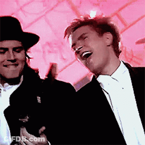 A Man In A Tuxedo Is Laughing Next To Another Man In A Top Hat GIF