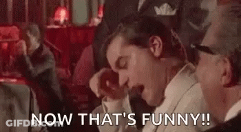 A Man In A Tuxedo Is Laughing With His Mouth Open While Sitting Next To Another Man . GIF