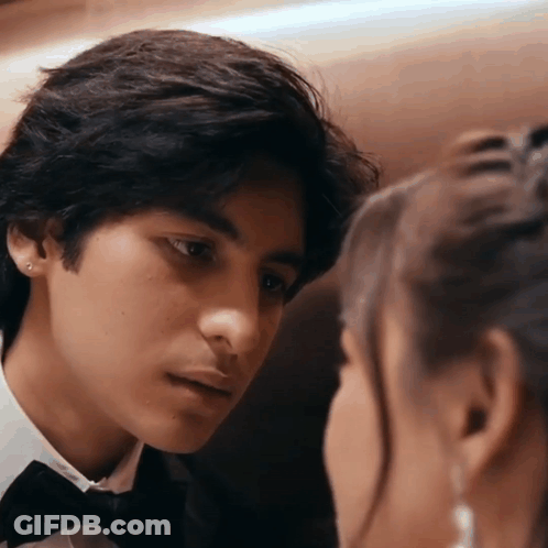 A Man In A Tuxedo Is Looking At A Woman In A White Shirt GIF