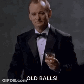 A Man In A Tuxedo Is Pointing At The Camera While Holding A Glass Of Whiskey . GIF