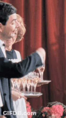 A Man In A Tuxedo Is Pouring Champagne Into A Tray GIF