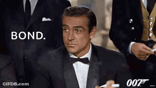 A Man In A Tuxedo Is Smoking A Cigarette And Says Bond GIF