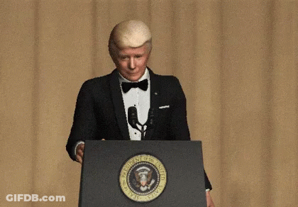 A Man In A Tuxedo Is Standing At A Podium With The Seal Of The President Of The United States On It GIF