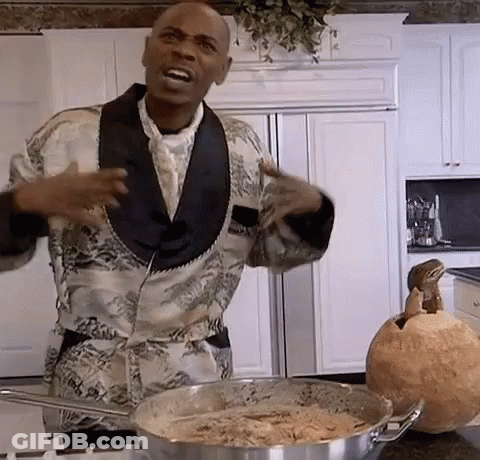 A Man In A Tuxedo Is Standing In A Kitchen Next To A Pot Of Food And A Pumpkin . GIF