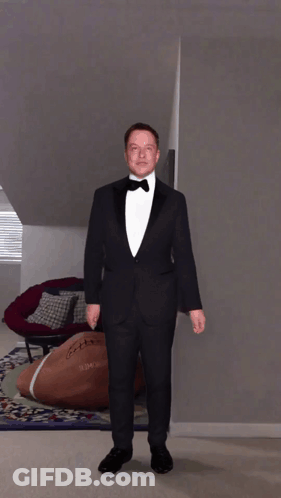 A Man In A Tuxedo Is Standing In A Room With A Football On The Floor GIF