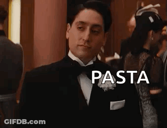 A Man In A Tuxedo Is Standing In A Room With The Word Pasta . GIF