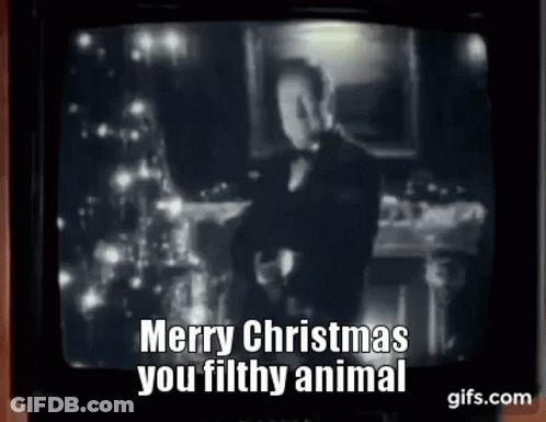 A Man In A Tuxedo Is Standing In Front Of A Christmas Tree On A Tv Screen . GIF