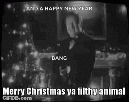 A Man In A Tuxedo Is Standing In Front Of A Christmas Tree With The Words Merry Christmas Ya Filthy Animal . GIF