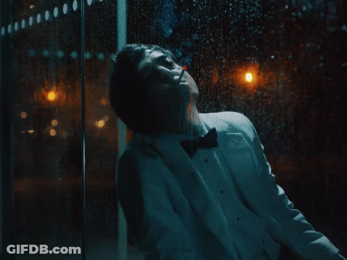 A Man In A Tuxedo Is Standing In Front Of A Window GIF