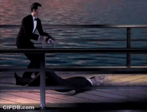 A Man In A Tuxedo Is Standing Next To A Dead Man On A Pier GIF