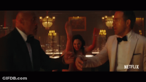 A Man In A Tuxedo Is Standing Next To A Woman In A Red Dress And A Man In A White Suit GIF