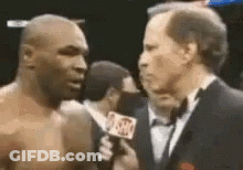A Man In A Tuxedo Is Talking To A Boxer . GIF