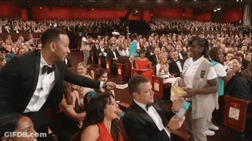 A Man In A Tuxedo Is Talking To A Girl Scout In A Crowd GIF