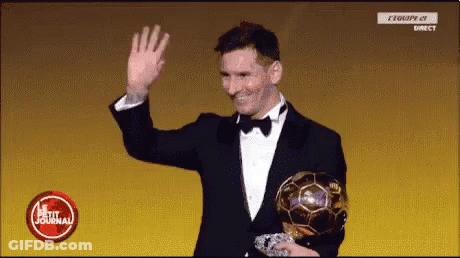 A Man In A Tuxedo Is Waving While Holding A Soccer Ball GIF