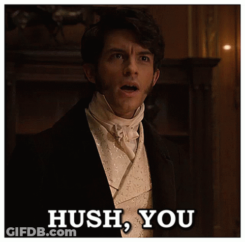 A Man In A Tuxedo Says Hush You In A Dark Room GIF