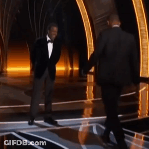 A Man In A Tuxedo Shakes Hands With Another Man In A Suit GIF