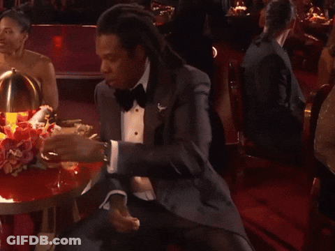 A Man In A Tuxedo Sits At A Table GIF