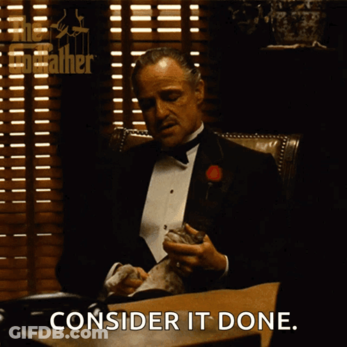 A Man In A Tuxedo Sitting At A Desk With The Words Consider It Done Written Below Him GIF