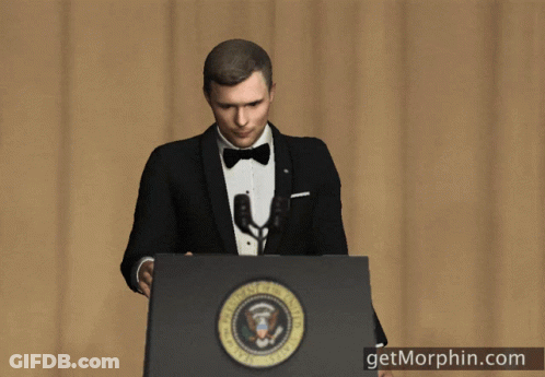 A Man In A Tuxedo Stands At A Podium With The Seal Of The President Of The United States GIF