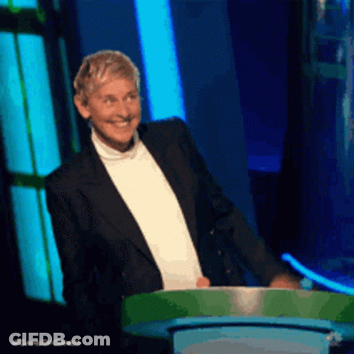 A Man In A Tuxedo Stands Behind A Green Podium With #Gameofgames Written On It GIF