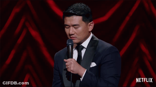 A Man In A Tuxedo Stands In Front Of A Microphone With Netflix Written On The Bottom GIF