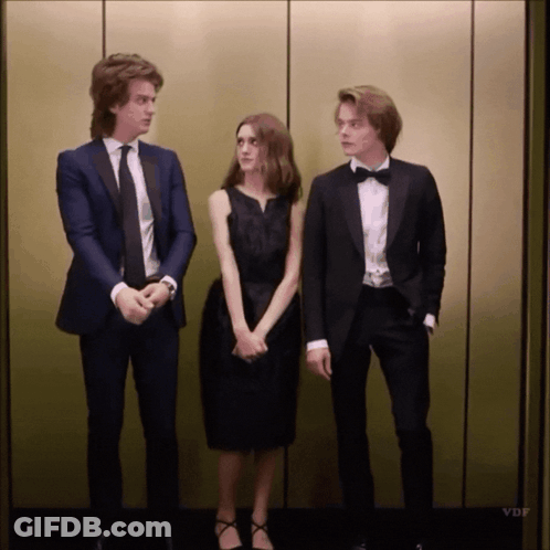 A Man In A Tuxedo Stands Next To A Woman In A Black Dress And A Man In A Bow Tie GIF