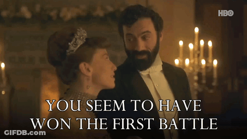 A Man In A Tuxedo Stands Next To A Woman In A Tiara With The Words You Seem To Have Won The First Battle GIF