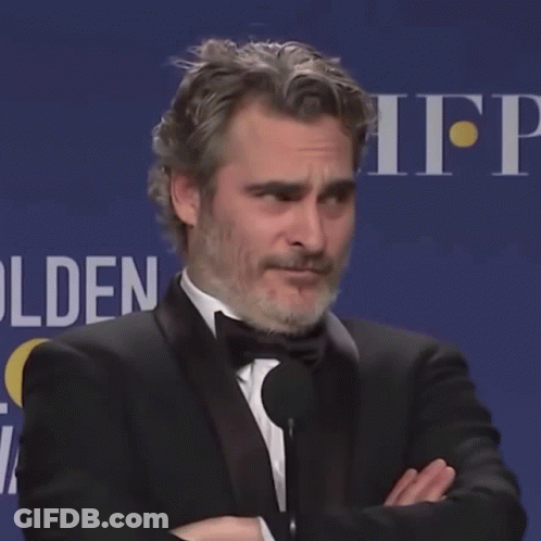 A Man In A Tuxedo Stands With His Arms Crossed In Front Of A Sign That Says Hfp GIF