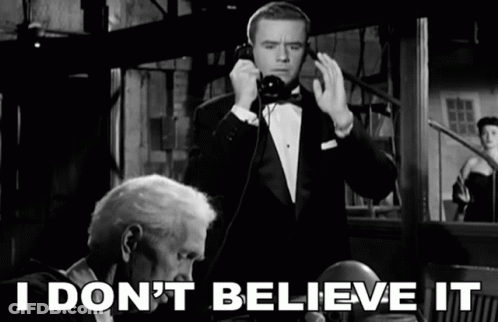 A Man In A Tuxedo Talking On A Phone With The Words " I Don 'T Believe It " Behind Him GIF