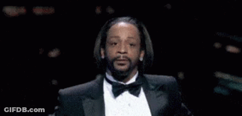 A Man In A Tuxedo With A Beard Is Making A Funny Face . GIF