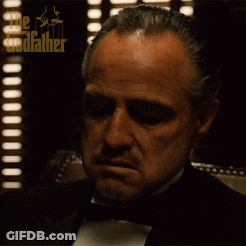 A Man In A Tuxedo With The Godfather Written On His Head GIF