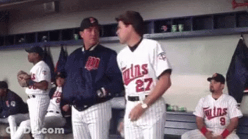 A Man In A Twins Jersey Talks To Another Man In A Dugout GIF
