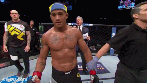 A Man In A Ufc Shirt Is Standing In A Boxing Ring GIF