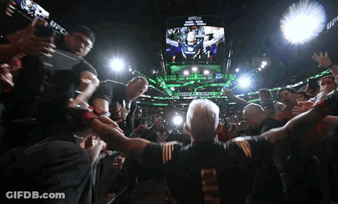 A Man In A Ufc Shirt Stands In Front Of A Crowd Of People GIF