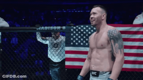 A Man In A Ufc Uniform Stands In Front Of A Madison 'S Banner GIF
