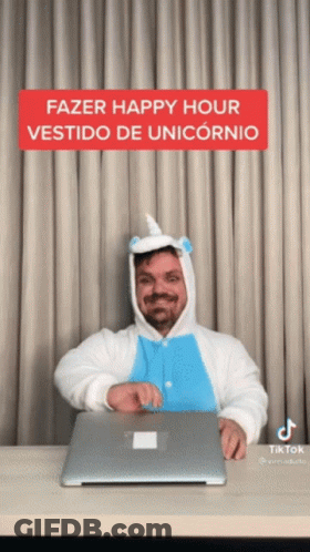 A Man In A Unicorn Costume Is Sitting At A Desk With A Laptop GIF