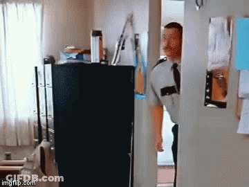 A Man In A Uniform And Tie Is Standing In A Doorway Looking Into A Room . GIF