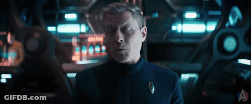 A Man In A Uniform With A Star Trek Logo On The Bottom Right GIF