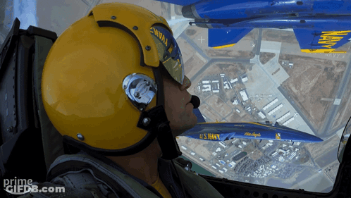 A Man In A Us Navy Helmet Looks Out The Window Of A Plane GIF
