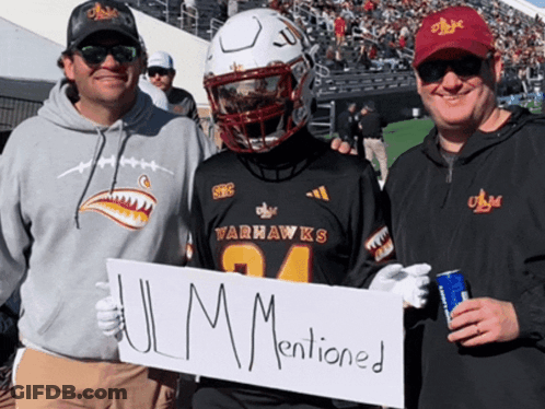 A Man In A Varhawks Jersey Holds A Sign That Says " Ulm Mentioned " GIF