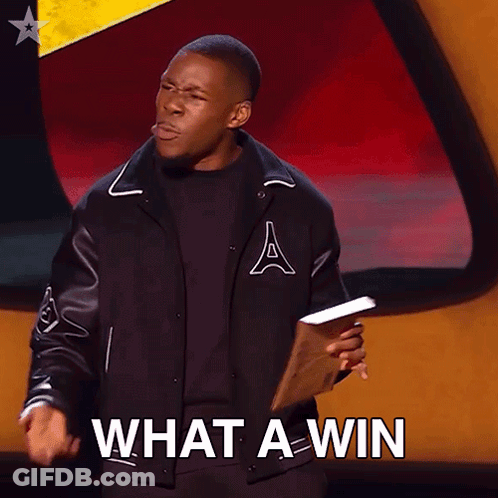 A Man In A Varsity Jacket Is Holding A Piece Of Paper And Says What A Win GIF