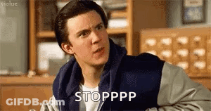 A Man In A Varsity Jacket Is Sitting In A Room And Making A Face . GIF