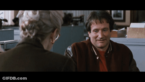 A Man In A Varsity Jacket Is Smiling While Talking To A Woman GIF