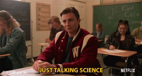 A Man In A Varsity Jacket With The Letter W On It Sits In A Classroom GIF