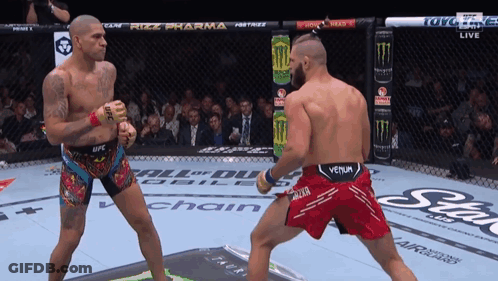 A Man In A Venum Shorts Is Fighting Another Man In A Ring GIF