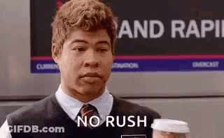 A Man In A Vest And Tie Is Holding A Cup Of Coffee And Saying `` No Rush '' . GIF