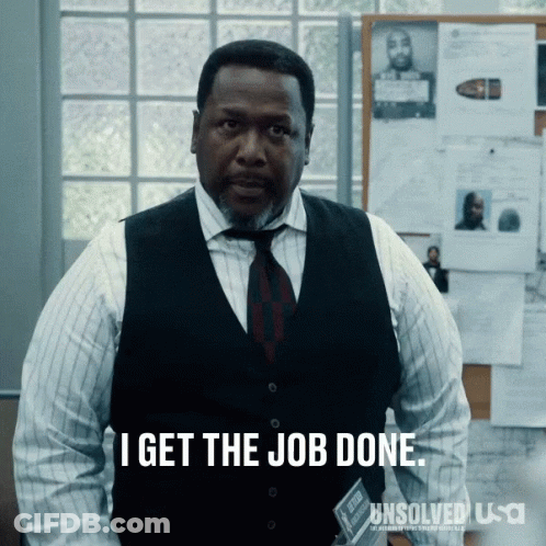 A Man In A Vest And Tie Is Standing In Front Of A Bulletin Board That Says I Get The Job Done GIF
