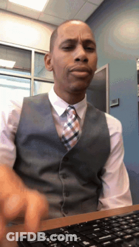 A Man In A Vest And Tie Sits At A Desk With A Keyboard GIF